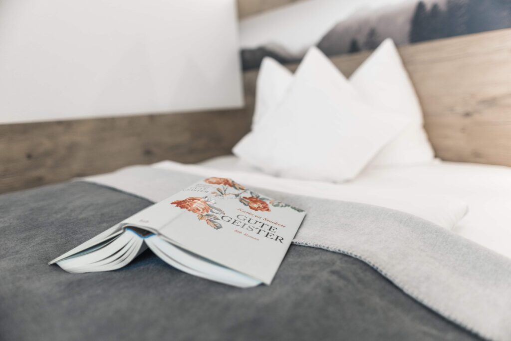 Stilvoll dekoriertes Bett mit einem offenen Buch